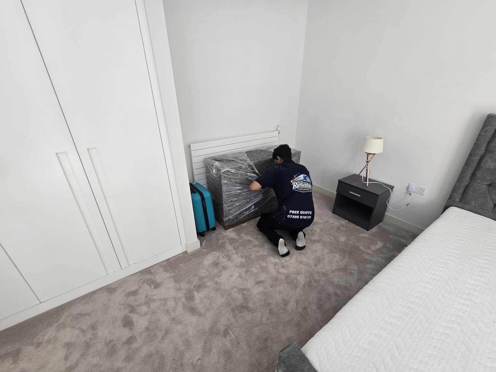 Mover unwrapping furniture in the bedroom of a new flat in Kingston upon Thames