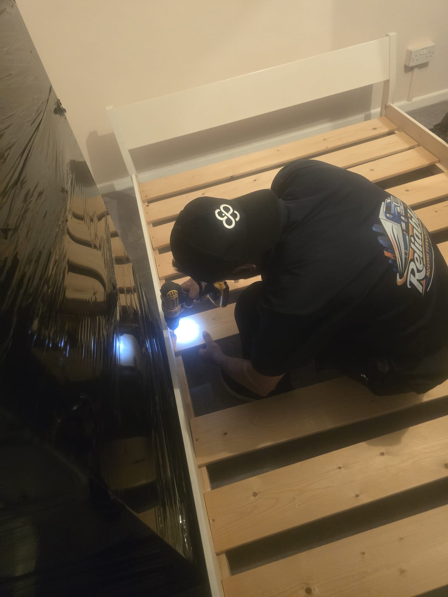 Reliable Moving Services mover assembling a wooden bed frame on a removal in Kingston