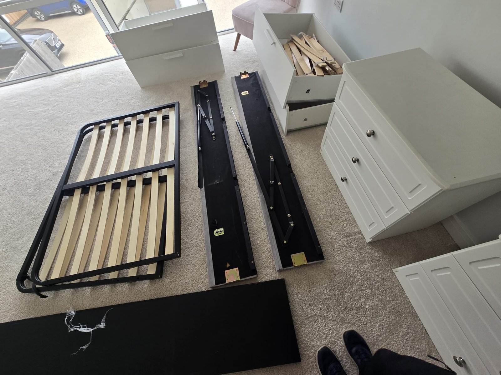 Bed frame taken apart and laid out ready for reassembly next to the chest of drawers